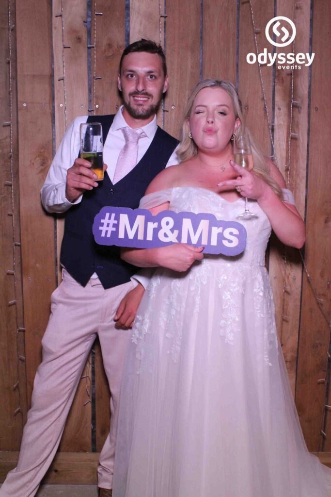 Bride and groom smiling in front of Odyssey Selfie Mirror at Chafford Park wedding photobooth