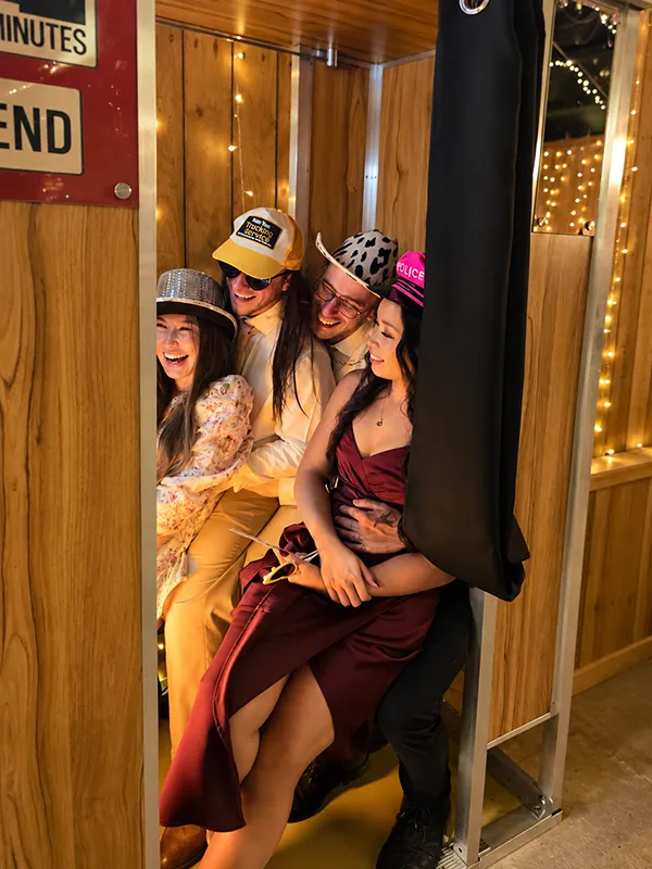 Four wedding guests laughing together inside the Odyssey Events Retrobooth at Chafford Park