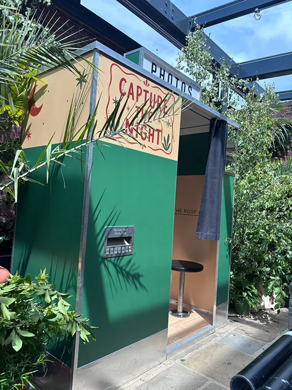 Green and cream enclosed photo booth installed in a landscaped London rooftop venue