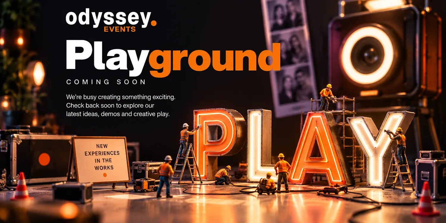 ext Miniature construction workers building illuminated PLAY letters, with photobooth equipment and Odyssey Events Playground coming soon branding.
