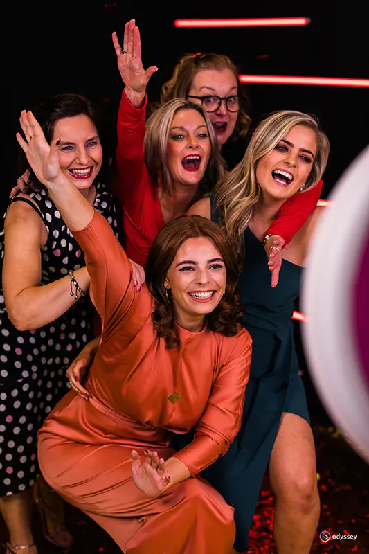 Five friends laughing and posing together during an interactive photo experience at a private celebration